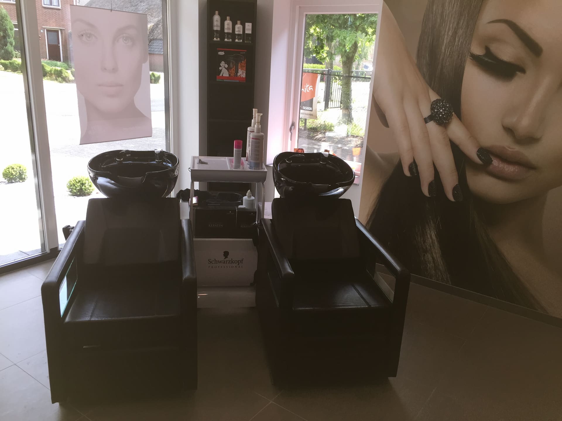 Twee wasplaatsen met zwarte stoelen in de kapsalon