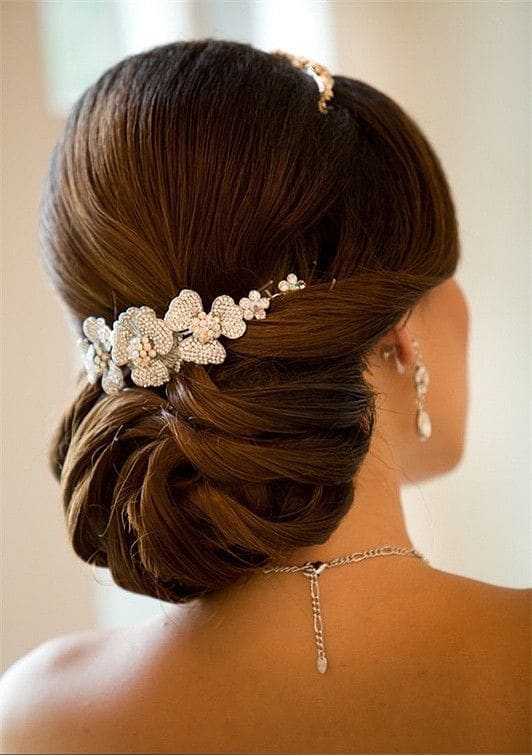 Laag opgestoken bruidskapsel met een bloemen haarsieraad