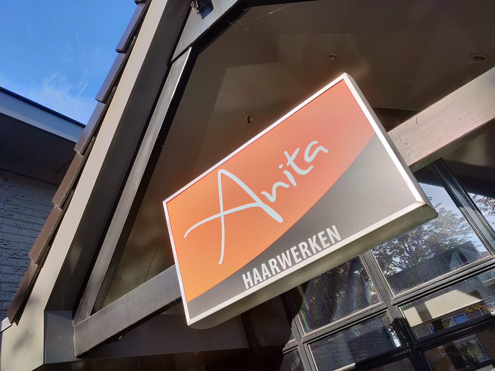 Het verlichte bord Anita Haarwerken aan de gevel